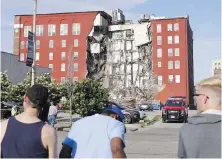  ?? QUAD CITY TIMES VIA AP ?? Onlookers watch as emergency crews work at the scene of a partial building collapse Sunday in Davenport, Iowa.