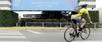  ?? NATACHA PISARENKO Associated Press ?? A MAN RIDES past a banner promoting the G20 summit at the Costa Salguero Center, in Buenos Aires. Thousands of police and security agents will guard the world leaders during the two-day meeting that starts tomorrow. |