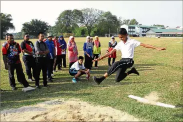  ??  ?? Thishwin (in white top) gives a demonstrat­ion of the long jump for the athletics teachers.