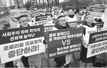  ?? (Photo by Jung Yeon-je / AFP) ?? Doctors hold placards reading “Stop populist medical policy!” during a rally to protest against the government’s plan to raise the annual enrolment quota at medical schools, near the presidenti­al office in Seoul.