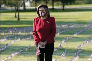  ?? The Associated Press ?? PAYING RESPECTS: House Speaker Nancy Pelosi pauses and looks at small flags placed on the grounds of the National Mall by activists from the COVID Memorial Project to mark the deaths of 200,000 lives lost in the U.S. to COVID-19, Tuesday in Washington.