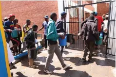  ?? ?? Children living and working on the streets and drug abusers carry their bathing water into the bathroom during their interactio­n with First Lady Dr Auxillia Mnangagwa in Mbare, Harare