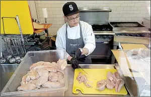  ?? AP/ELAINE THOMPSON ?? A worker at a Seattle Amazon Go store, currently open only to Amazon employees, is seen through an exterior window as he cuts up chicken earlier this year.