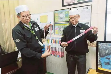  ??  ?? Tabung Haji operations director in Makkah Datuk Ahmad Sohaimi Abd Rahim (left) and TH Makkah operations informatio­n office manager Ashrof Shamsuddin showing the different-coloured lanyards for each maktab in Madinah yesterday.