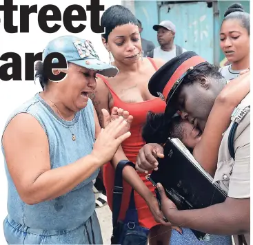  ??  ?? Inspector Jacqueline Ricketts, sub-officer in charge of Gold Street Police Station, comforts Julia Hird (centre), mother of 11-year-old Taysha Hughes, yesterday. Taysha was shot dead near her home on Fleet Street, Central Kingston, on Thursday night.