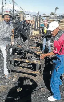  ?? Picture: BHONGO JACOB ?? GUTTED: Mzamomhle residents in Section E collect what they could salvage of their belongings from a fire that left one person dead on Saturday evening