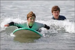  ??  ?? ( Below) Lily Astrakhan, 11, gets a push from Nathan Domke during her first surf session at the Surf’s Up SCV camp at Mondos Beach in Ventura.