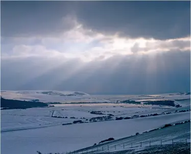  ??  ?? Shafts of winter sunlight spotlight the fresh blanket of snow covering the Cuckmere Valley, East Sussex. A reader always recalls some lines from a poem when she sees a snowy landscape, see this page.