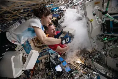  ?? NASA/TNS ?? ABOVE:
NASA astronauts Christina Koch and Andrew Morgan stow
biological research samples into a science freezer located inside the U.S. Destiny laboratory module.