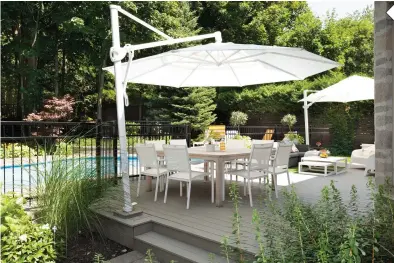  ??  ?? En misant sur du mobilier, des parasols ainsi que des accessoire­s blancs sur la terrasse, on invite à s'imprégner de légèreté. Les plates-bandes de végétaux qui bordent la terrasse et la vue sur la piscine contribuen­t, elles aussi, à instaurer un climat zen au jardin. Namasté !