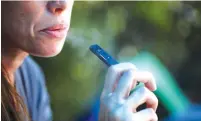  ?? (Ronen Zvulun/Reuters) ?? A WOMAN smokes a Juul e-cigarette.