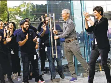  ?? Kena Betancur AFP via Getty Images ?? APPLE CEO Tim Cook, second from right, at the company’s store on Fifth Avenue in New York. Apple requires its workers to submit to exit searches of their bags, packages purses, backpacks, briefcases and devices.