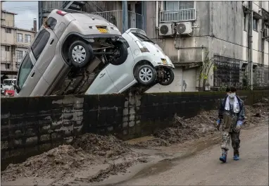  ??  ?? These cars were swept up against a wall after torrential rain caused floods in Hitoyoshi, Japan, killing at least 60 people