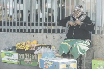  ?? Picture: Yeshiel Panchia ?? WRAPPED UP. Shelina Chabalala braces against the cold as she sells her wares on Main Reef Road in the CBD of Johannesbu­rg yesterday as the city was hit by a strong cold front.