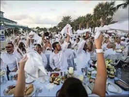  ?? BRUCE R. BENNETT / THE PALM BEACH POST ?? Guests wave their white linen serviettes to signal the beginning of dinner at Diner en Blanc at Riviera Beach Marina Village.