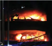  ?? The Associated Press ?? Vehicles burn during a blaze at a multi-storey car park at the Echo Arena on the waterfront in Liverpool, England on Sunday. Up to 1,400 vehicles were reduced to ashes in the blaze, but nobody was reported injured.