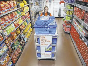  ??  ?? Alice Ribitch, a personal shopper at Walmart, fills customer orders for pickup.