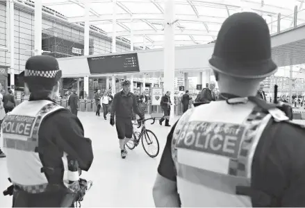  ?? Associated Press ?? Police watch Tuesday as commuters pass through the Manchester Victoria railway station in Manchester, England, which has reopened for the first time since the terror attack on the adjacent Manchester Arena. The station was closed following the...