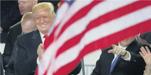  ??  ?? > President Donald Trump watches the Inaugural Parade from the main reviewing stand in front of the White House