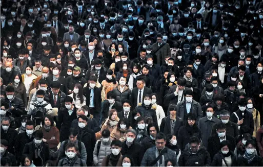  ?? CHARLY TRIBALLEAU AFP VIA GETTY IMAGES ?? Most commuters were wearing masks as they made their way to work on Friday during morning rush hour at the Shinagawa train station in Tokyo.