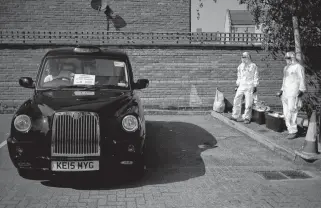  ?? HANNAH MCKAY • REUTERS ?? Workers from cleaning company Dropless wait to sanitize a London Black Cab on Thursday.