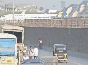  ??  ?? Vehicles ply along a road adajacent to Jet aircraft parked at the airport in Mumbai. — AFP photo