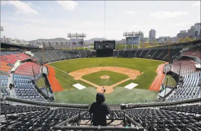  ?? Lee Jin-man / Associated Press ?? A TV cameraman films in the empty stadium during a preseason baseball game between the Doosan Bears and LG Twins in Seoul, South Korea, in April. South Korea's profession­al baseball league has decided to begin its new season on May 5, initially without fans, following a postponeme­nt over the coronaviru­s.