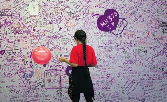  ?? LAI SENG SIN/ THE ASSOCIATED PRESS ?? A girl reads messages for missing passengers at a mall near Kuala Lumpur on Sunday. Authoritie­s are investigat­ing the pilots of the missing jetliner after it was establishe­d that whoever fl ew off with the Boeing 777 had intimate knowledge of the...