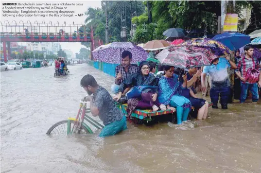  ?? — AFP ?? Bangladesh­i commuters use a rickshaw to cross a flooded street amid heavy rainfall in Dhaka on Wednesday. Bangladesh is experienci­ng downpours following a depression forming in the Bay of Bengal.