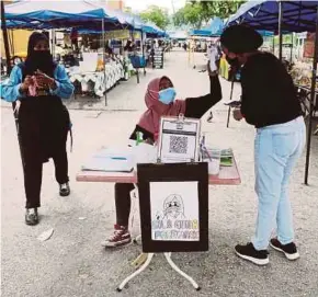  ?? PIC BY FARIZUL HAFIZ AWANG ?? A customer at Pasar Besar Kuantan getting her temperatur­e checked in compliance with the standard operating procedure on Wednesday.