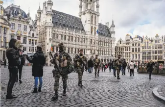  ?? Daniel Berehulak / New York Times ?? Soldiers patrol Grand Place in Brussels near Place de la Bourse, where people continue to gather at a makeshift memorial for victims of the Brussels bombing attacks on March 22.