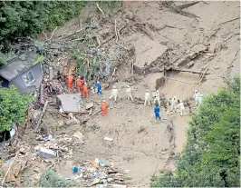  ??  ?? Rescuers in Takehara where a mudslide crushed scores of homes