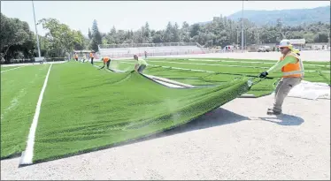  ?? PHOTO BY GEORGE SAKKESTAD ?? Workers install artificial turf on the football field at Los Gatos High School. The local chapter of the Sierra Club has come out against the proposed installati­on of artificial turf on elementary and middle school campuses, citing environmen­tal and health concerns.