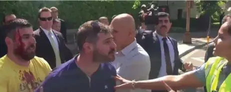  ?? VOICE OF AMERICA NEWS VIDEO ?? Alpkenan Dereci, in the yellow T-shirt, is seen holding back Ahmet Dereci, who is shouting at a Washington, D.C. police officer last week.