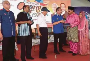  ?? BERNAMA PIC ?? Defence Minister Datuk Seri Hishammudd­in Hussein handing over land grants to Husin Ismail and his wife, Saniah Saleh, in Felda Ulu Belitong, Kluang, Johor, yesterday. Looking on is Tan Sri Shahrir Abdul Samad (third from left).