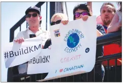  ?? Canadian Press photo ?? Pro-Kinder Morgan demonstrat­ors look on as Prime Minister Justin Trudeau makes an infrastruc­ture announceme­nt in Calgary, Tuesday.