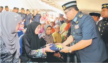  ??  ?? RMAF Air Support commander Lt Jen Datuk Wan Normazlan Che Jaafar hands over the Jalur Gemilang to Mohd Hasri’s wife, Assyuhadak Ahmad at the funeral for the pilot who died in the crash. — Bernama photo