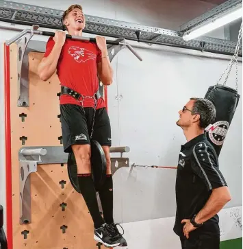  ?? Foto: Siegfried Kerpf ?? Gut gelaunt in der Folterkamm­er des Curt Frenzel Stadions: AEV Talent Marco Sternheime­r macht Klimmzüge vor den Augen von Fitnesscoa­ch Sven Herzog für die neue Eishockey Saison.