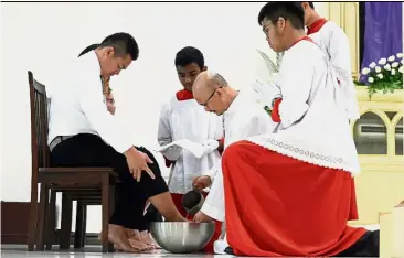  ?? By AMALINA AKASHAH ?? Sacrifice and gratitude: Father Alberto washing the feet of Barry Joy Nusip during the Maundy Thursday service at the Church of St Francis Xavier in Petaling Jaya.