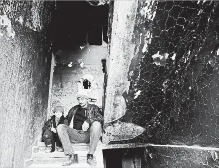  ?? HASSAN AMMAR THE ASSOCIATED PRESS FILE PHOTO ?? Mohammed Bayraqdar poses with his son Abdul-Awal at their burned house in Khaldiyeh, one of the worst damaged areas in Homs, Syria.