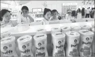  ?? ZHANG TAO / FOR CHINA DAILY ?? Customers pick imported milk powder cans at an e-trade