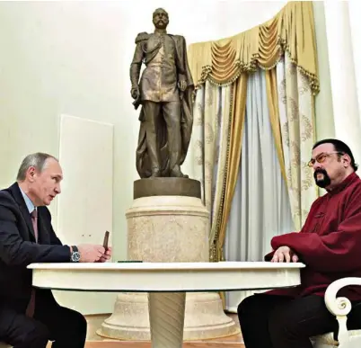  ?? (SPUTNIK/KREMLIN/ALEXEI DRUZHININ VIA REUTERS) ?? Vladimir Poutine un passeport russe à la main, en 2016, à l’intention de Steven Seagal.