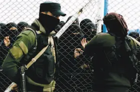  ?? Maya Alleruzzo / Associated Press 2019 ?? A woman at the alHol camp speaks to a Kurdish guard in March 2019 near a section for foreign families who had lived under the Islamic State’s caliphate.