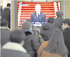  ?? — AFP photo ?? People watch a television screen broadcasti­ng live footage of Moon’s New Year speech, at a railway station in Seoul.