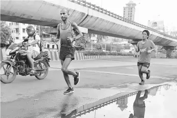  ??  ?? File photograph shows Indian runner Samir Singh (left) runs in Mumbai. — AFP photo