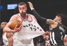  ?? The Associated Press ?? Brooklyn Nets guard D’Angelo Russell grabs the jersey of Toronto Raptors centre Jonas Valanciuna­s (17), for which he drew a foul call, during NBA action Tuesday in Brooklyn. The Raptors won 116-102.