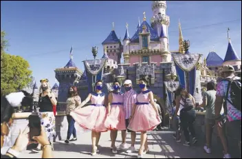  ?? ASSOCIATED PRESS ?? A family takes a photo Friday in front of Sleeping Beauty’s Castle at Disneyland in Anaheim. The iconic theme park, which was closed under the state’s strict virus rules, swung open its gates Friday, and some visitors came in cheering and screaming with happiness.