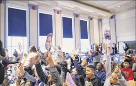  ??  ?? Students in the Albany Internatio­nal Center school hold up cards with the photo of teacher Christina Zontini and her boyfriend, Terry Burke, to cheer them during an assembly at the school on Thursday.