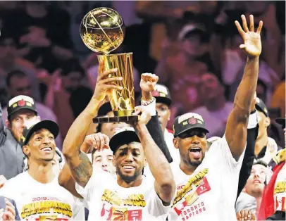  ?? (AP) ?? TORONTO Raptors forward Kawhi Leonard (center) holds the Larry O'Brien NBA championsh­ip trophy after the Raptors defeated the Golden State Warriors, 114-110, in Game 6 of the 2019 NBA Finals in Oakland, California.