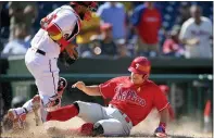  ?? NICK WASS - AP ?? The Phillies’ J.T. Realmuto, right, slides home to score on a double by Andrew McCutchen as Nationals catcher Keibert Ruiz, left, fields the late throw during the sixth inning of a baseball game, Thursday, in Washington. The Phillies won 7-6.